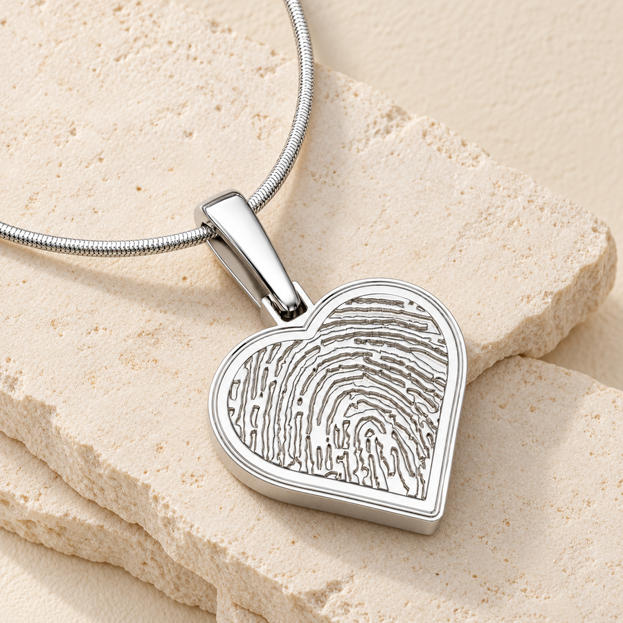 Sterling silver fingerprint heart necklace on cream stone.
