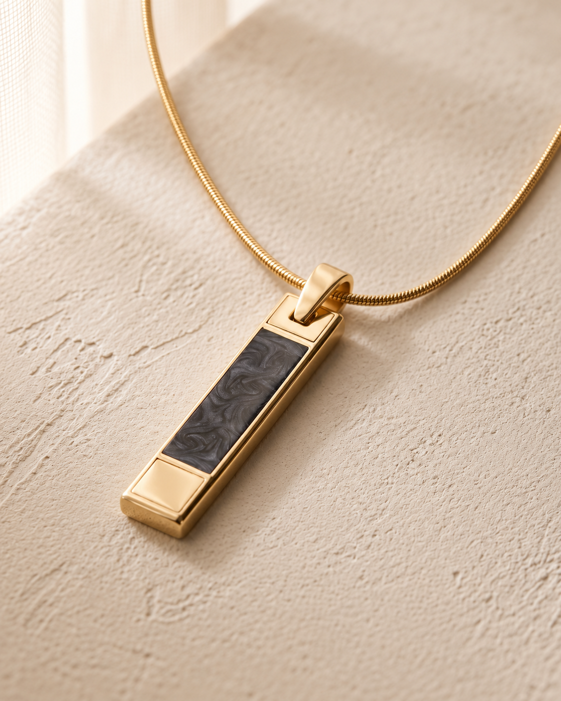 Gold End of Day ash resin pendant with one continuous gold snake chain on cream stone
